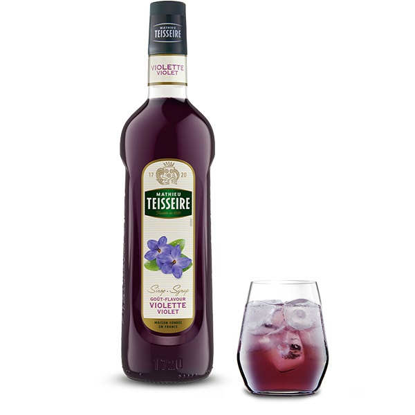 Bottle of Mathieu Teisseire Violette Violet syrup with a glass of the syrup on a white background