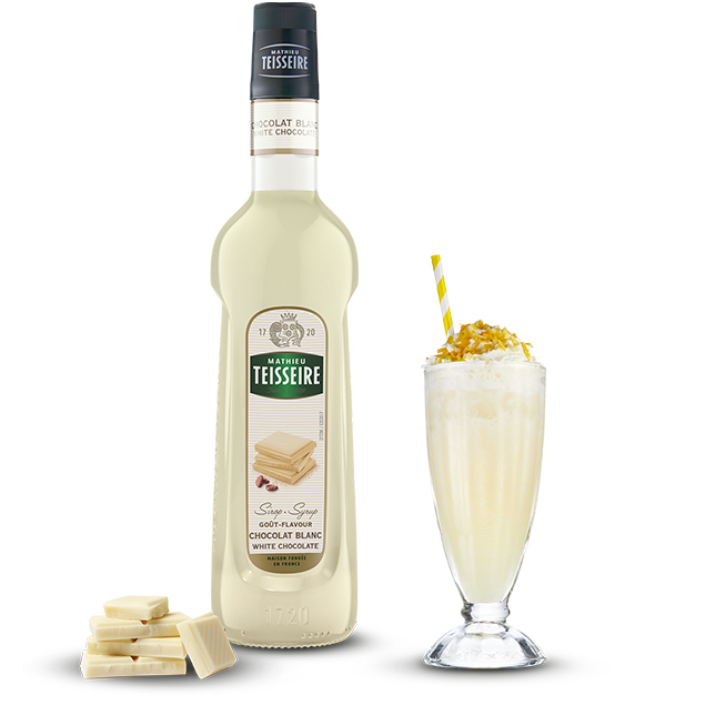 Bottle of Teisseire white chocolate syrup with a glass of dessert and white chocolate pieces on a white background