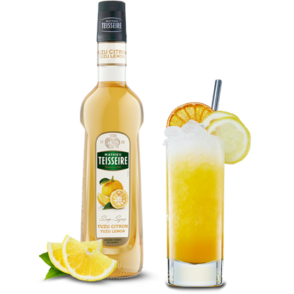 Bottle of Teisseire Yuzu Citron syrup with a glass of lemon-themed cocktail on a white background