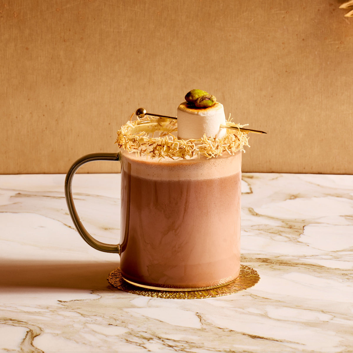 Hot chocolate with marshmallows and chocolate shavings on a marble surface with a gold background