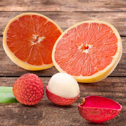 Two grapefruits cut in half and two lychees on a wooden surface