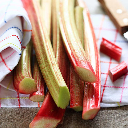 Stalks of rhubarb on a checkered cloth with a knife in the background