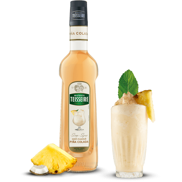 Bottle of Teisseire Pina Colada syrup with a cocktail and pineapple garnish on a black background