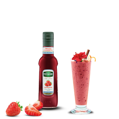 Teisseire strawberry syrup bottle with a strawberry milkshake and strawberries on a white background