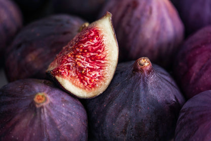 Close-up of purple figs with a halved fig showing red flesh.